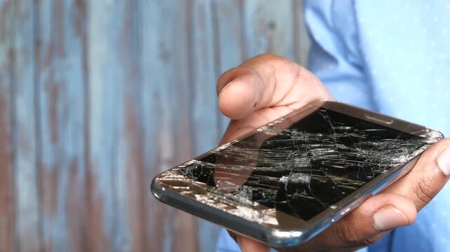 Person holding a damaged smartphone with cracked screen up close motion