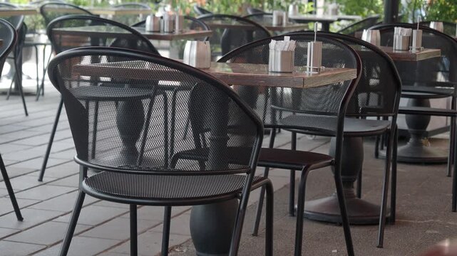 Empty outdoor cafe tables and chairs set up for diners on sunny day