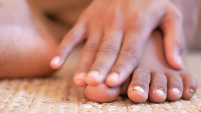 Close up footage of a person gently touching their toes with their fingers, slow motion