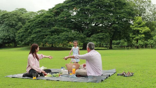Father, Little girl walking and spending time with father in the park. Happy Asian family having fun time on picnic at city nature park, outdoor activitie
