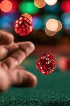 Hand throwing translucent red dice on green table