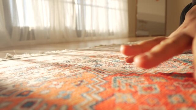 Person hand feeling texture of traditional oriental carpet in sunlight