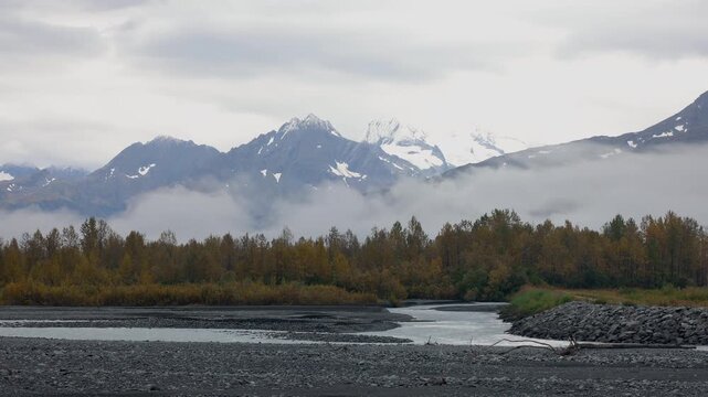 Alaskan river flowing through a valley with snowy mountains, time lapse.