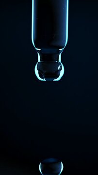 Vertical macro shot of a blue copper peptide or hyaluronic acid serum droplet falling in slow motion from a glass pipette dropper isolated on a dark background