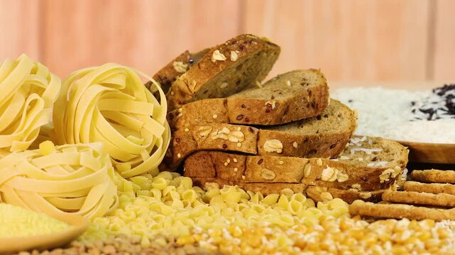 Slow motion camera movement across variety of healthy complex carbohydrates including whole grain bread and pasta.