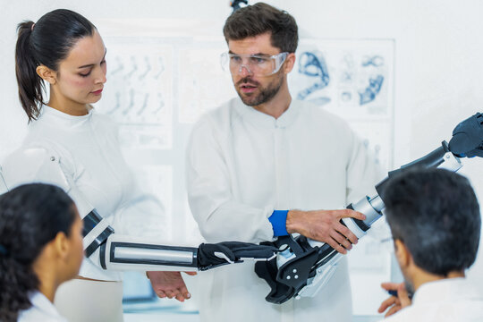 Machine learning robotics lab: researchers lower a complete robotic arm onto the bench, ready to record the next batch of motion data from its shoulder and elbow