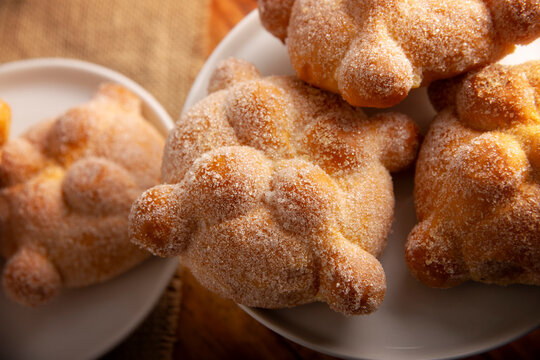 Pan de Muerto. Traditional Mexican sweet bread coated with sugar on white plates, perfect for Day of the Dead.