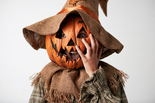 Pumpkin-Head Scarecrow Costume on White Background with Halloween Witch Hat Burlap Collar and Playful Frightened Expression