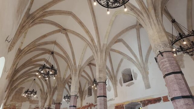 Ornate chandeliers beneath ribbed Gothic vaults inside Corvin Castle in Hunedoara Romania