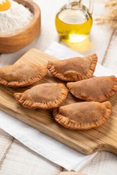 Crispy golden fried mini chebureki meat turnovers served on wooden cutting board with rustic ingredients