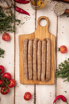 Raw chicken sausages arranged neatly on wooden cutting board ready for cooking