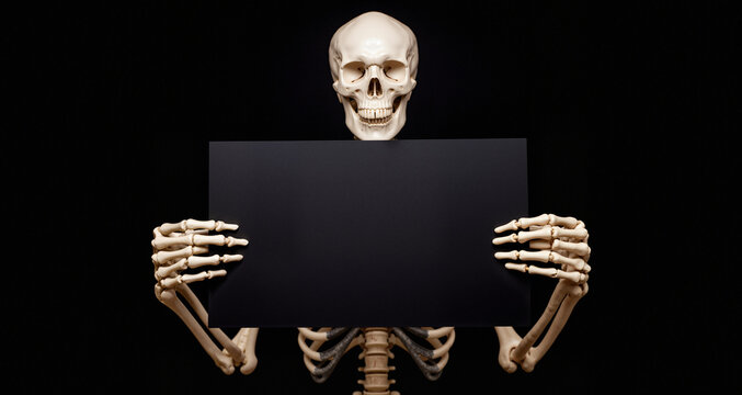 Skeleton holding black empty card on black background mockup for Halloween card
