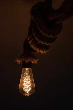 A transparent globe light bulb with orange filaments inside a sailor rope.