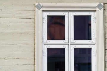 Fototapeta premium Multi pane timber window with decorative trim set into painted wooden cladding, illustrating traditional facade joinery and exterior building envelope components