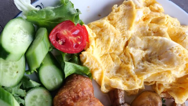 A close up cinematic view of freshly prepared omelet and healthy salad on white plate ready for breakfast or brunch