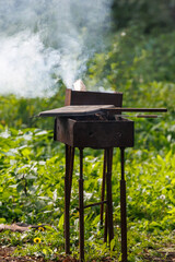 Fototapeta premium Smoke rises from a rusty outdoor grill