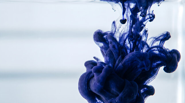 Indigo ink dropping and swirling in clear water macro background
