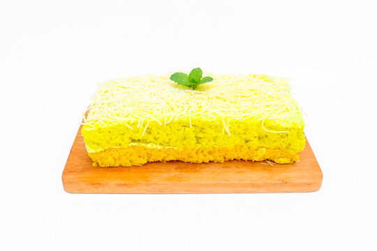 Delicious avocado flavored cake topped and filled with creamy frosting, generously covered with fine shredded cheese and garnished with fresh mint leaves isolated on white background