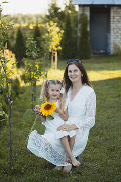 a cute five-year-old girl with mother in a white dress are playing in a green summer garden. happy childhood