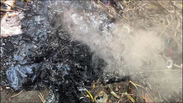 White smoke rising from charcoal and burnt organic waste outdoors