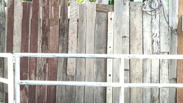 A weathered wooden wall behind white metal railing background.