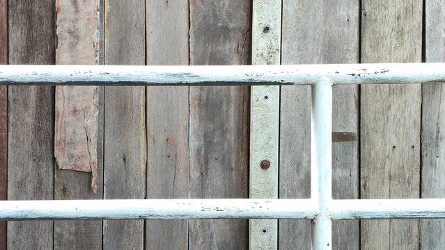 A weathered wooden wall behind white metal railing background.