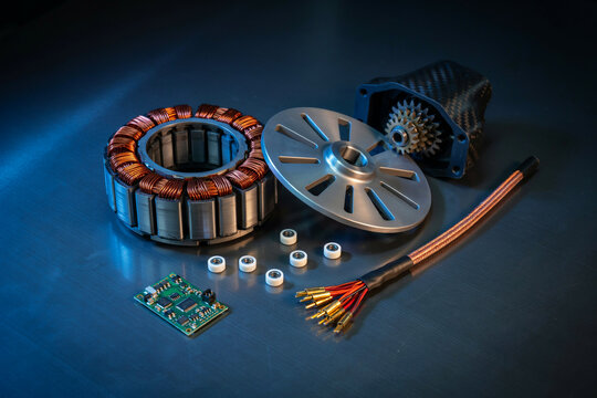 Electric motor parts consisting of a copper wire stator, a silver rotor, a gear housing, small ball bearings, a circuit board, and a cable