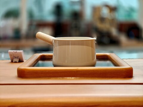 Ceramic saucepan with wooden handle on a cooking surface in a modern kitchen with soft blurred background.