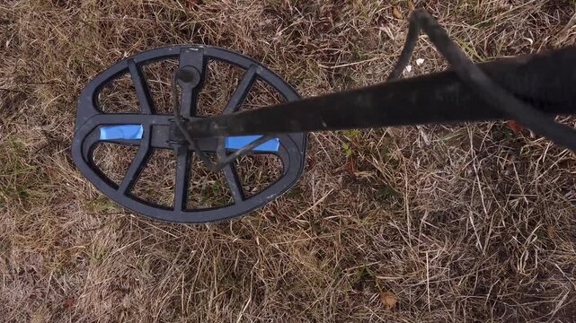 Treasure hunter with metal detector search coins in field 
