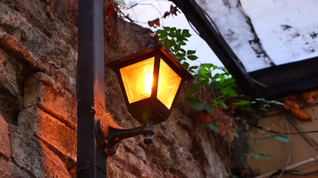 Classic lantern lighting up stone wall in evening street scene