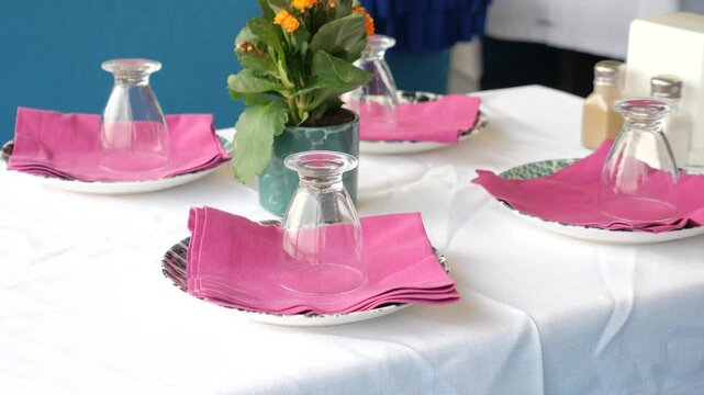 Table setting with pink napkins glasses and plant for dining