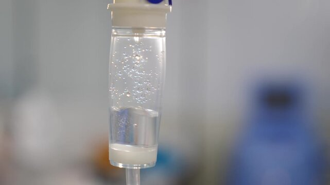 Close-up of IV drip chamber with clear liquid and rising bubbles. Medical infusion setup in hospital, sterile equipment, healthcare treatment, patient care, clinical environment 4k video