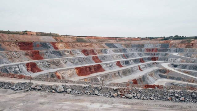 Wide terraced open pit quarry with a haul road spiralling down the benches