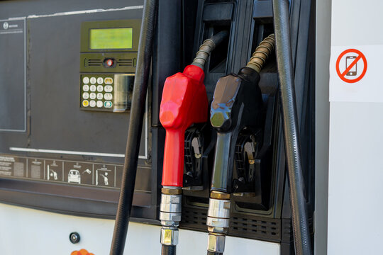 Gasoline pumps with red and black nozzles ready for refueling vehicles