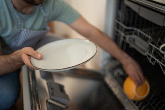 Man loading dirty dishes into modern dishwasher