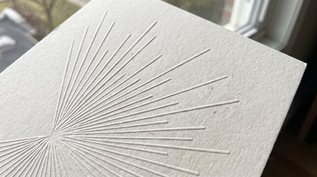 Minimalist embossed sunburst pattern on textured handmade cotton paper card. Concept of letterpress, card mockup, sun rays, stationery, blind deboss. Copy space.