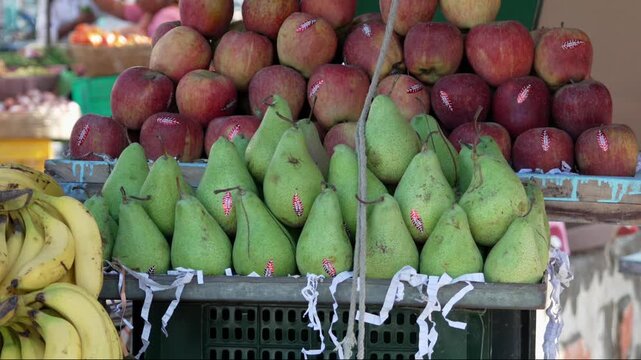 Fresh red apples and green pears stacked on fruit market display stall