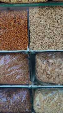 Assorted traditional Indian snacks, namkeen, and sev displayed in glass showcase at market stall