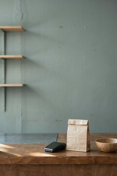 Card terminal and paper bag on a worn oak shop counter after closing