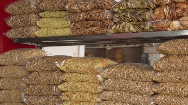 Assorted varieties of crunchy Indian sev and namkeen packed in clear plastic bags on store shelves