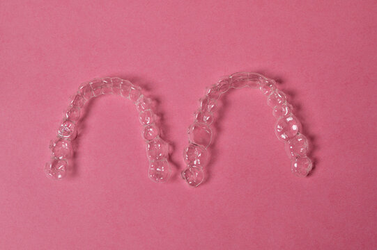 Clear aligners for teeth straightening on pink background