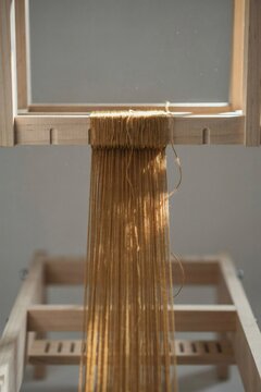Bundle of ochre threads lifted from one loom frame and rethreaded above it