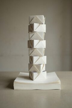 Tower of folded paper modules rising from a stack of blank cream sheets