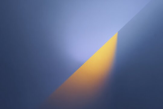 A blue background with a yellow light shining through it creating a contrast between the two colors. the light is radiating from the center of the giving it a warm and inviting glow.