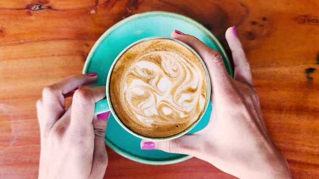 4K shot of Girl grab coffee in cafe. Pretty young woman enjoying morning drink, female customer in coffee shop with big cup of coffee latte. Girl grabs a cup of hot coffee with milk during morning bre