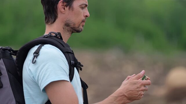 Traveler with backpack photographing wild nature using smartphone, enjoying peaceful freedom and open exploration