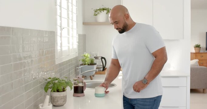 Lifestyle videos indoor of people doing activities at home, man standing in kitchen holding coffee c