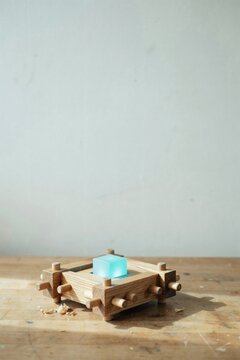 Hand built wooden jig of pegged rails holding one luminous cube in alignment