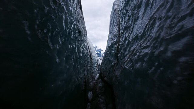 Dynamic FPV drone flight skimming above and between deep glacier crevasses on glacier, Iceland. Cinematic aerial footage revealing blue ice formations and dramatic glacial landscape.