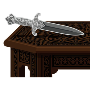 Decorative silver dagger resting on carved wooden antique table.